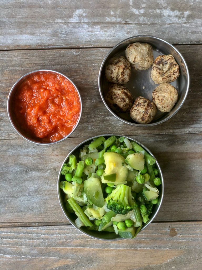 Cooked mixed greens and meatballs with marinara sauce