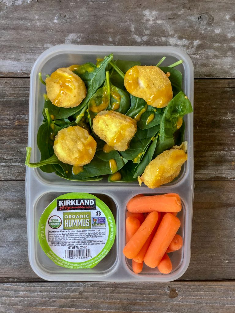 GF chicken nuggets on top of spinach with honey mustard dressing, carrots, mini hummus - easy costco lunches