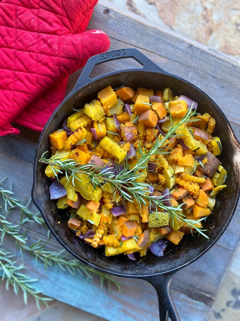 Roasted root vegetables in a skillet with fresh rosemary on top